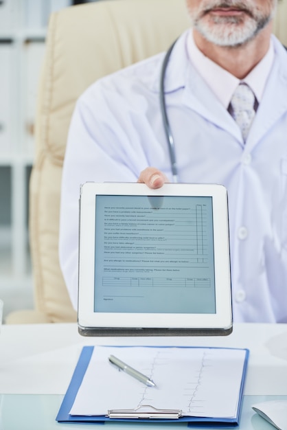 A doctor reviewing a patient's chart during a check-up, symbolizing the healthcare benefits and comprehensive care provided through Medicaid expansion.