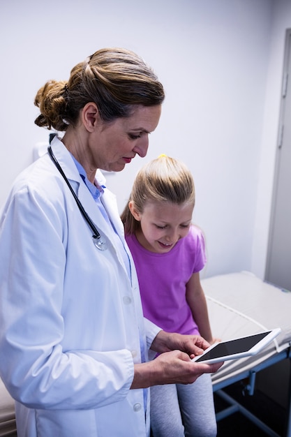 A close-up of a doctor reviewing medical records with a concerned parent, while a child with a disability sits quietly nearby. The scene emphasizes the importance of medical documentation in the SSI application process.