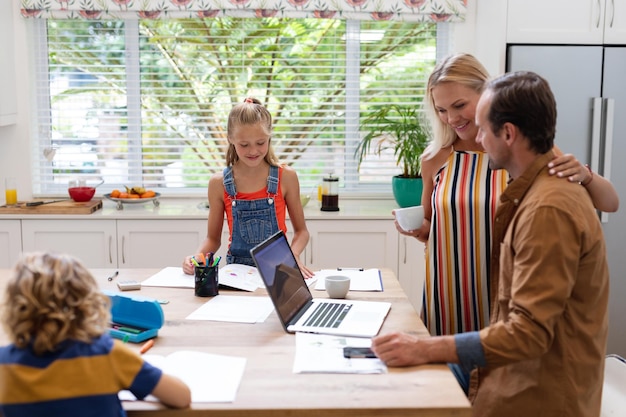 A family sitting at a table reviewing tax documents together, with a laptop displaying the IRS website and icons representing tax forms and updates.