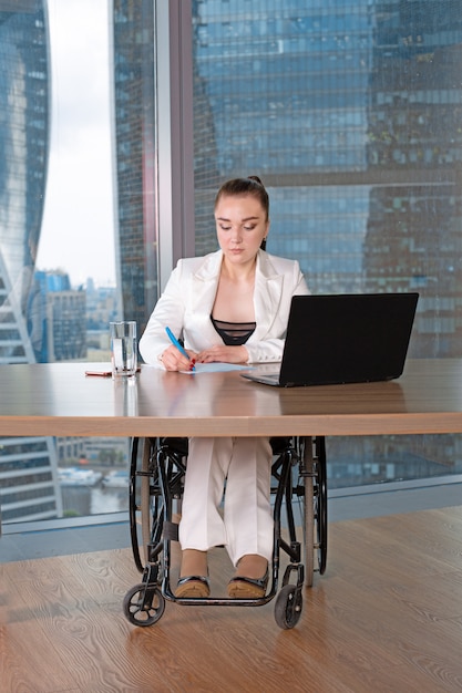 An office setting where a person using a wheelchair is working comfortably at a height-adjustable desk. The scene emphasizes inclusivity and how reasonable accommodation can enable individuals with disabilities to thrive in the workplace.