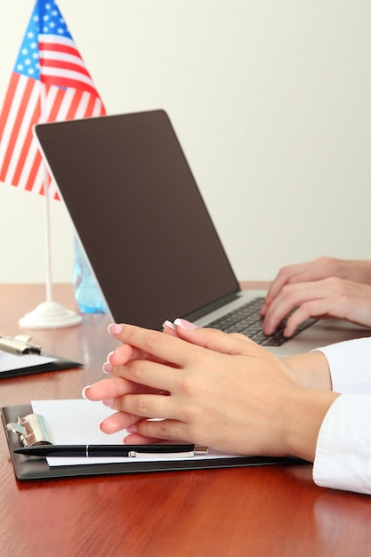 A veteran filling out a disability benefits application form at a desk, with a laptop displaying the VA website in the background.