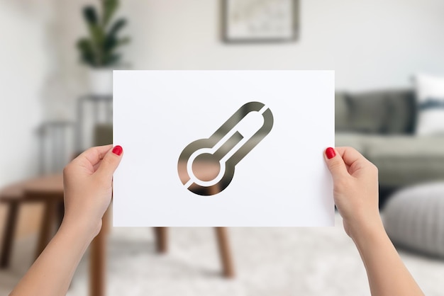 A close-up of a hand holding a thermostat, emphasizing the act of adjusting the temperature to conserve energy. The focus is on the individual effort in reducing energy consumption. A blurred image of family and love in frame for a cozy, healthy environment.