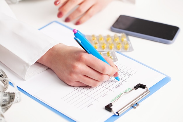 A close-up shot of a hand holding a pen, filling out a Medicare application form. The form is partially visible, displaying sections for income and asset declaration. A calculator rests nearby.