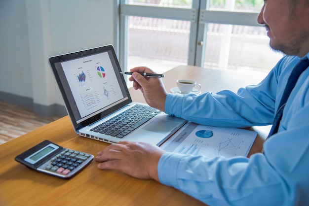 A person using a laptop to analyse a detailed financial report, complete with graphs and charts that indicate income, expenses, and savings, signifying a thorough assessment of their financial health.