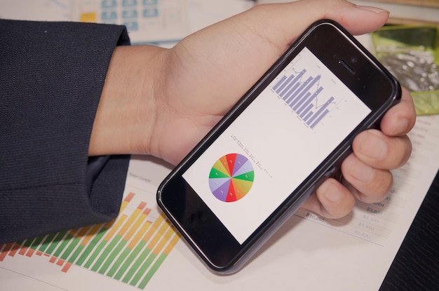 A close-up shot of someone using a budgeting app on their smartphone, with pie charts and graphs illustrating income and expenses. The image highlights the use of technology for financial tracking and planning.