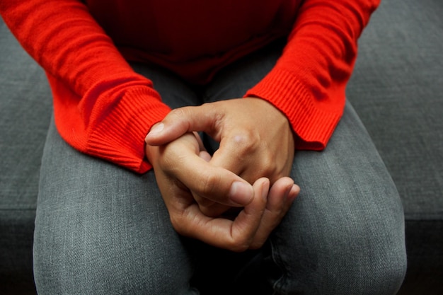A close-up shot of a person’s hands clasped tightly together, fingers intertwined, conveying a sense of anxiety and stress. The background is blurred, emphasizing the emotional aspect.