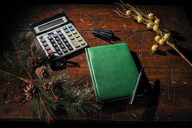 A hand writing in a budgeting notebook, with a calculator and various bills scattered around. The scene is set on a wooden desk with a warm, focused light.