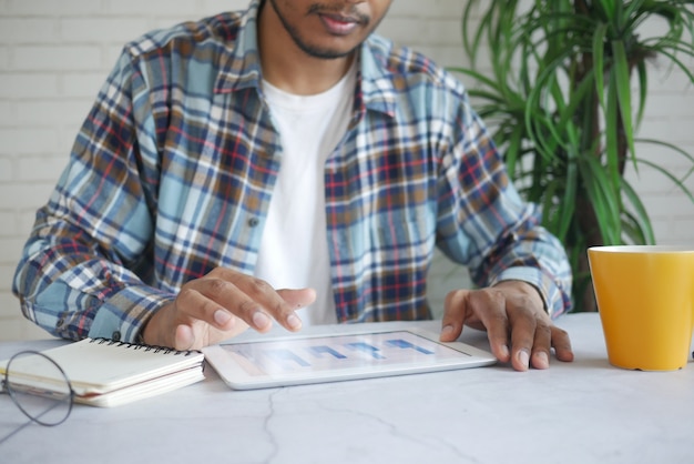 A person sitting at a desk, using a budgeting app on their tablet, with charts and graphs displayed, visualizing the process of analyzing income and expenses for financial planning.