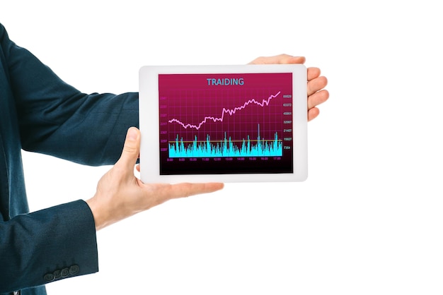A person holding a tablet showing a stock market graph with upward trends, representing successful investment and financial growth. The background includes office elements and a window view of a city skyline.