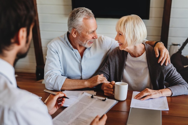 A senior couple reviewing estate planning documents with a financial advisor in a well-lit office, emphasizing the importance of professional guidance.