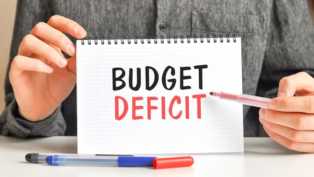 A person crossing out various expenses from a budget list with a red marker, including items like cable TV, subscription services, and dining out, symbolizing the process of cutting unnecessary spending.