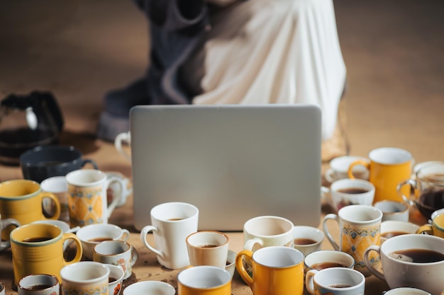 A person working on a laptop at a coffee shop, surrounded by books and a cup of coffee, illustrating the freedom and flexibility associated with gig work.