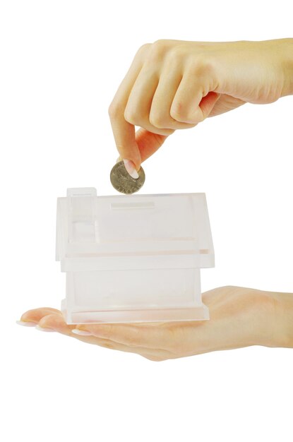 A hand holding miniature house on coins base.