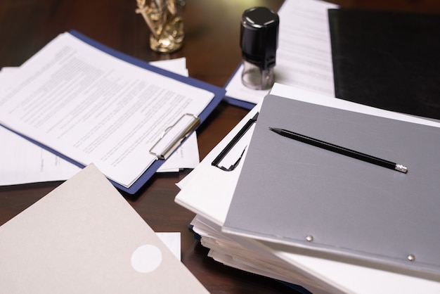 A close-up shot of legal documents related to business compliance, including certificates and tax forms, arranged neatly on a desk with a pen and a pair of glasses.
