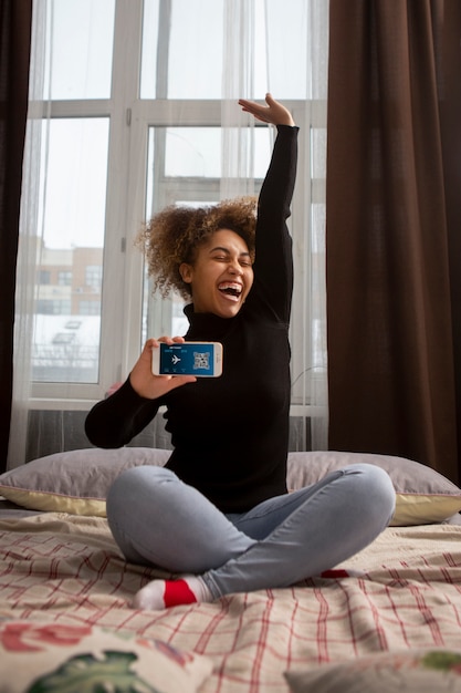 A person smiling while using a mobile app on their phone, showing a balance of earned rewards. The background shows a glimpse of a comfortable home setting.