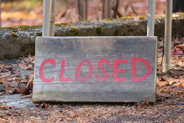 An image depicting a closed sign hanging on the entrance to a national park, with disappointed families in the background, symbolizing the impact of a government shutdown on recreational services.
