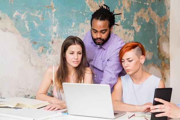 A diverse group of students looking concerned while gathered around a laptop displaying news headlines about the Supreme Court's decision on student loans. The scene emphasizes the real-world impact on students.