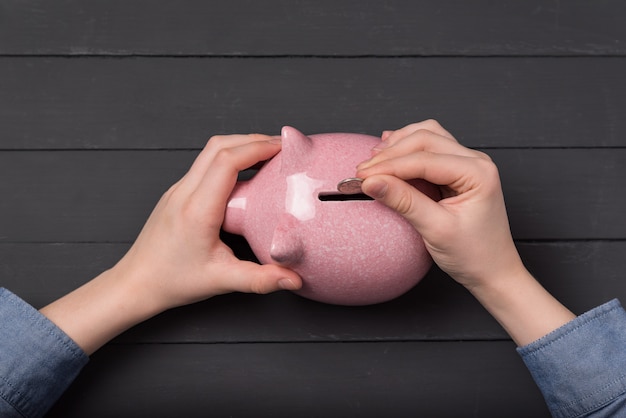 A close-up shot of hands placing coins into a piggy bank, symbolizing retirement savings and financial planning.