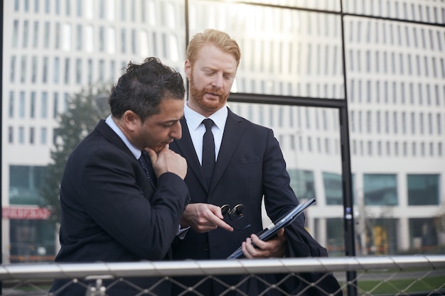 A professional setting showing a lawyer in a suit, reviewing a client's Social Security Disability claim documents with them. The atmosphere is collaborative, suggesting trust and expertise.