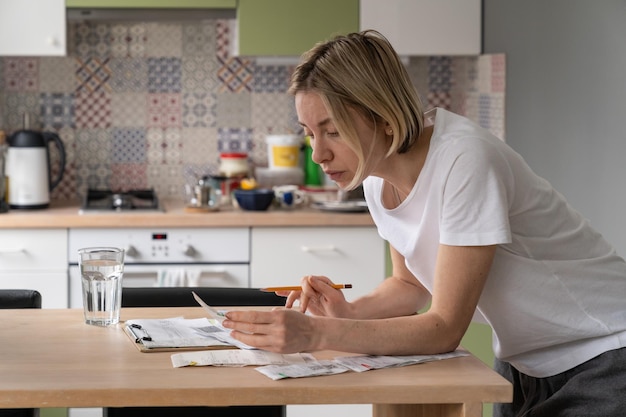 A person organizing bills and paperwork at a kitchen table, with a calculator and a cup of coffee nearby. The focus is on managing household expenses and documenting deductions for SNAP benefits.