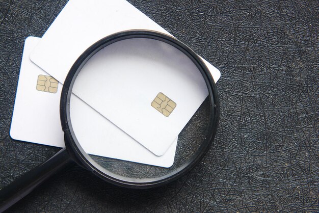 Close-up of a credit card with a magnifying glass over it, symbolizing the need for careful monitoring of credit card usage and payment history to maintain a good credit score.