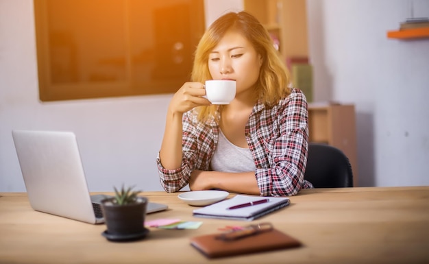 A person sitting at a desk, thoughtfully writing in a notebook, surrounded by pens, a laptop, and a cup of coffee, symbolizing the planning phase of starting a business.