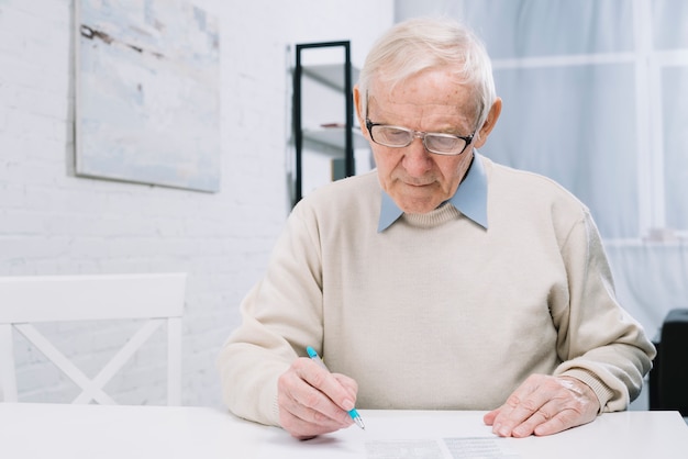An elderly man sitting at a table with various brochures and papers related to Medicare Part D plans. He appears thoughtful and engaged in comparing different options.