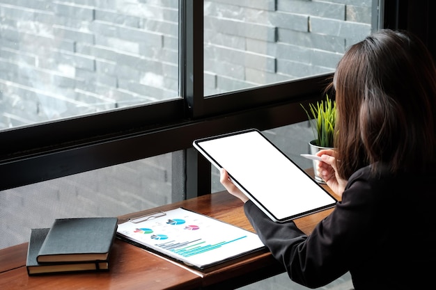 A person using tax preparation software on a tablet, with charts and graphs representing financial data visible on the screen. The setting suggests a home office environment.