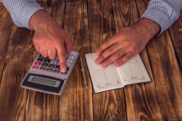 A digital calculator showing the debt-to-income ratio formula and a person's hands typing on a calculator.