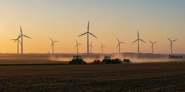 Modern farm with tractors and wind turbines at sunrise